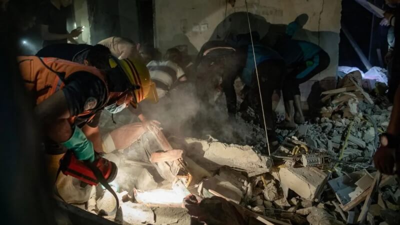 Palestinos buscan personas desaparecidas bajo los escombros de una casa tras un ataque aéreo israelí en el campo de refugiados de Rafah.