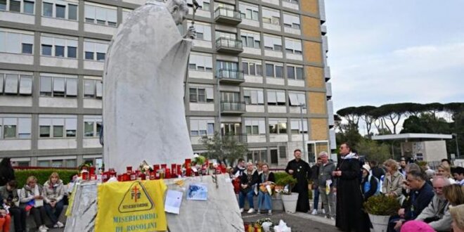 Fieles rezan ante la estatua de Juan Pablo II en el exterior del Hospital Gemelli, donde se encuentra internado el Papa Francisco. Foto AFP